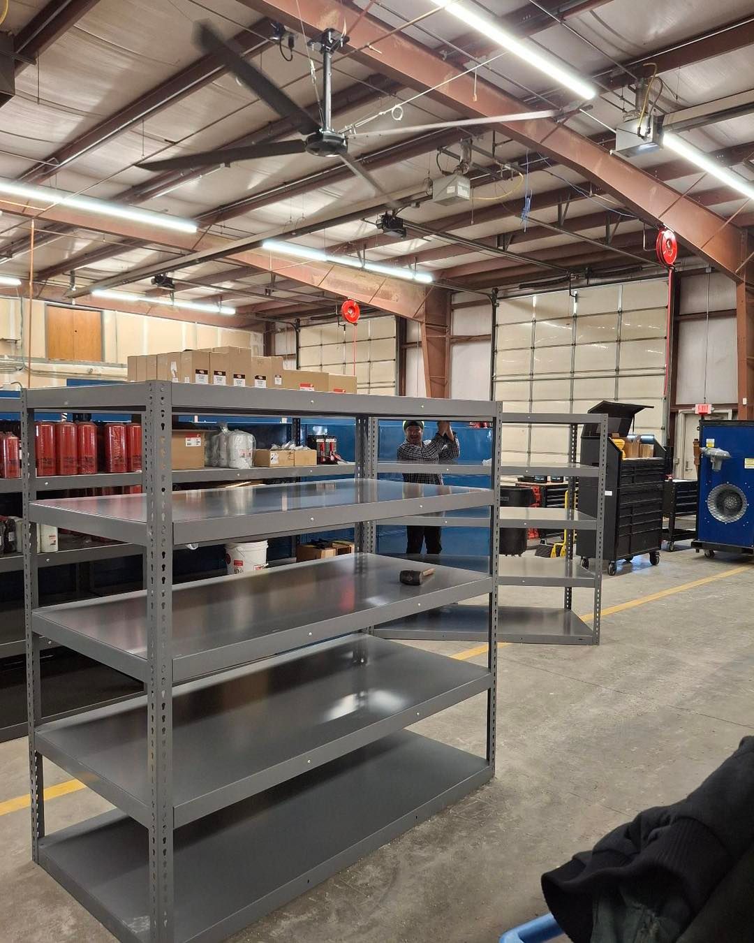 A warehouse with a lot of shelves and a ceiling fan.