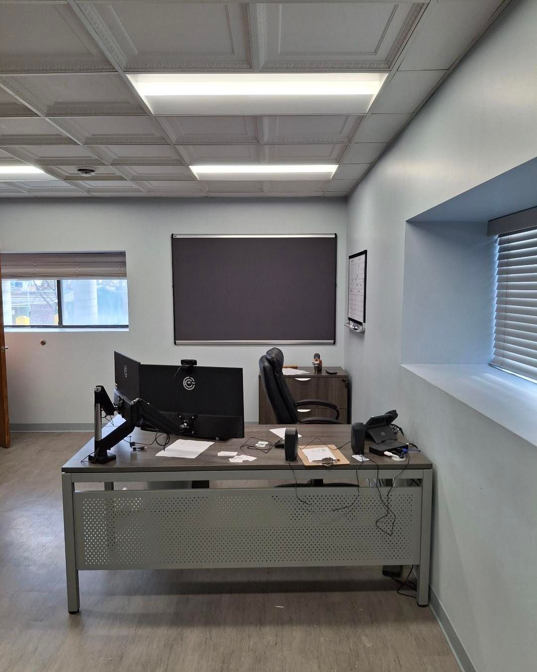 A desk with a computer and a chair in an office.