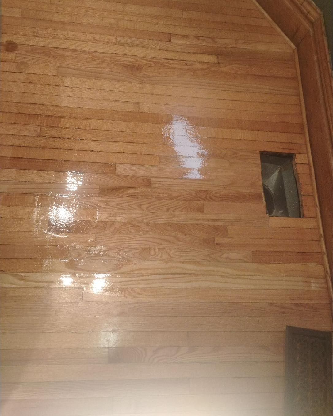 A close up of a wooden floor with a hole in the wall.