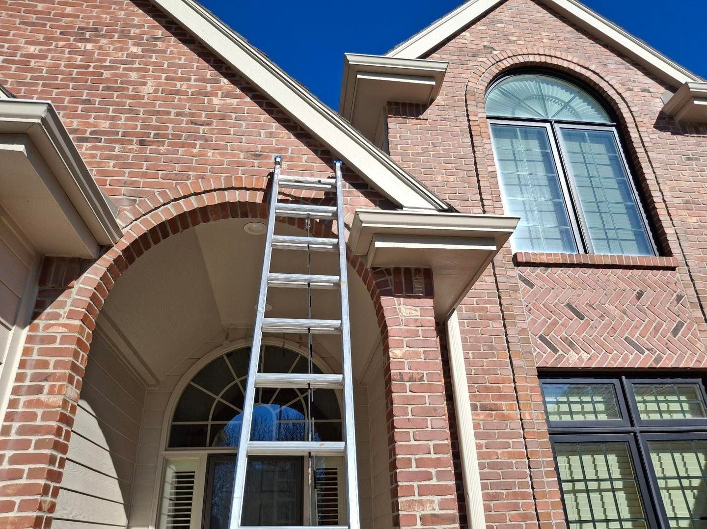 A ladder is hanging from the side of a brick house.