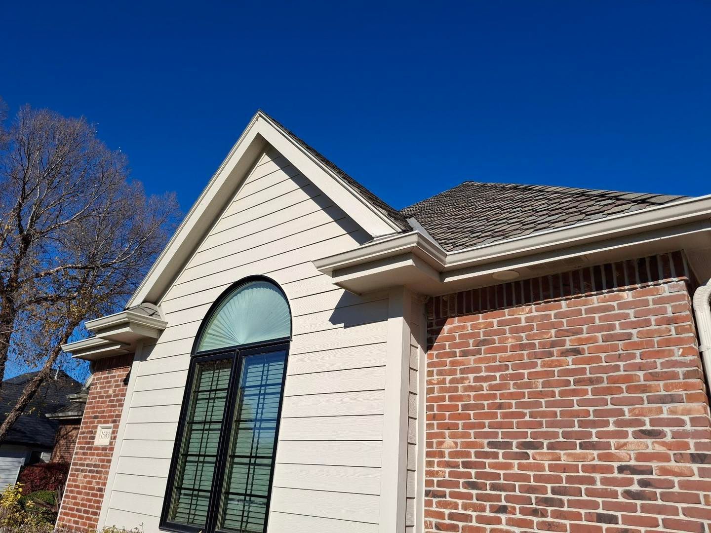 A brick house with a white siding and a roof.