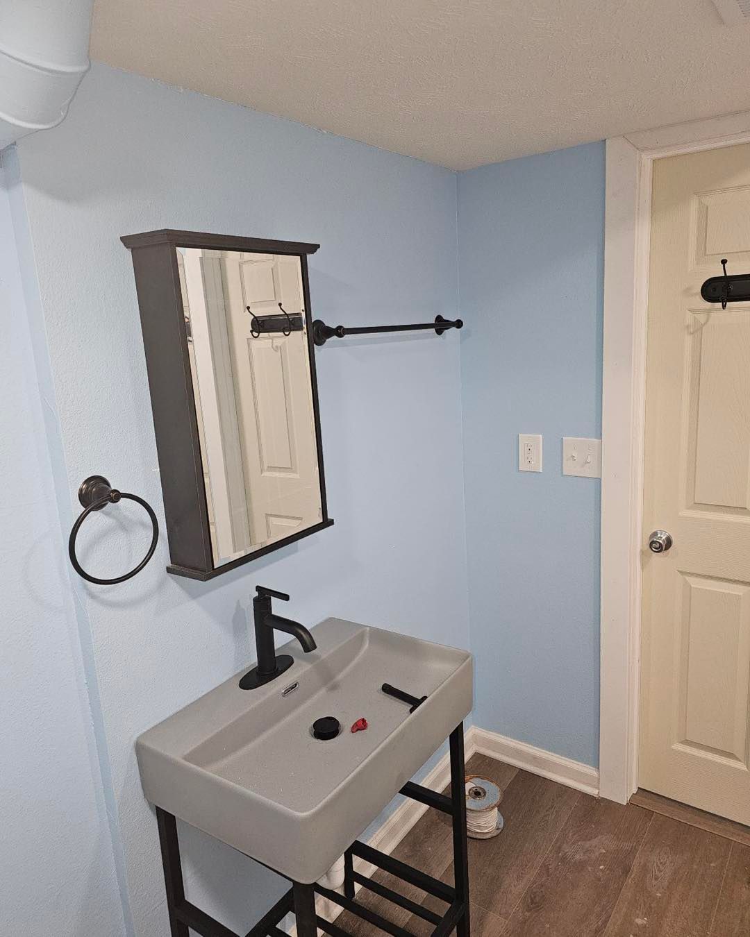 A bathroom with a sink, mirror, and towel rack.