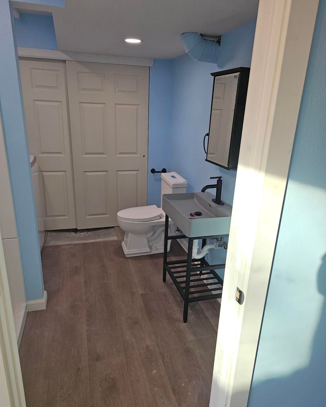 A bathroom with a toilet, sink, and mirror.