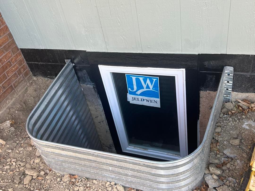 A window in a basement window well with a jw logo on it.