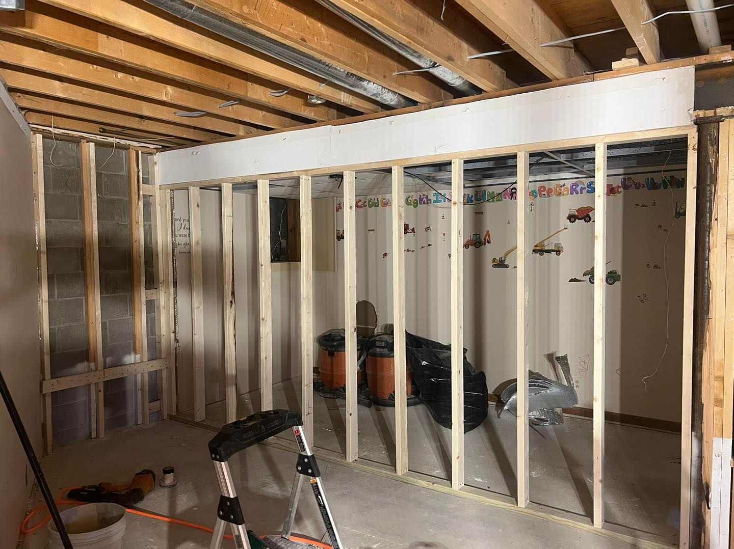 A room with wooden beams and a ladder in it.
