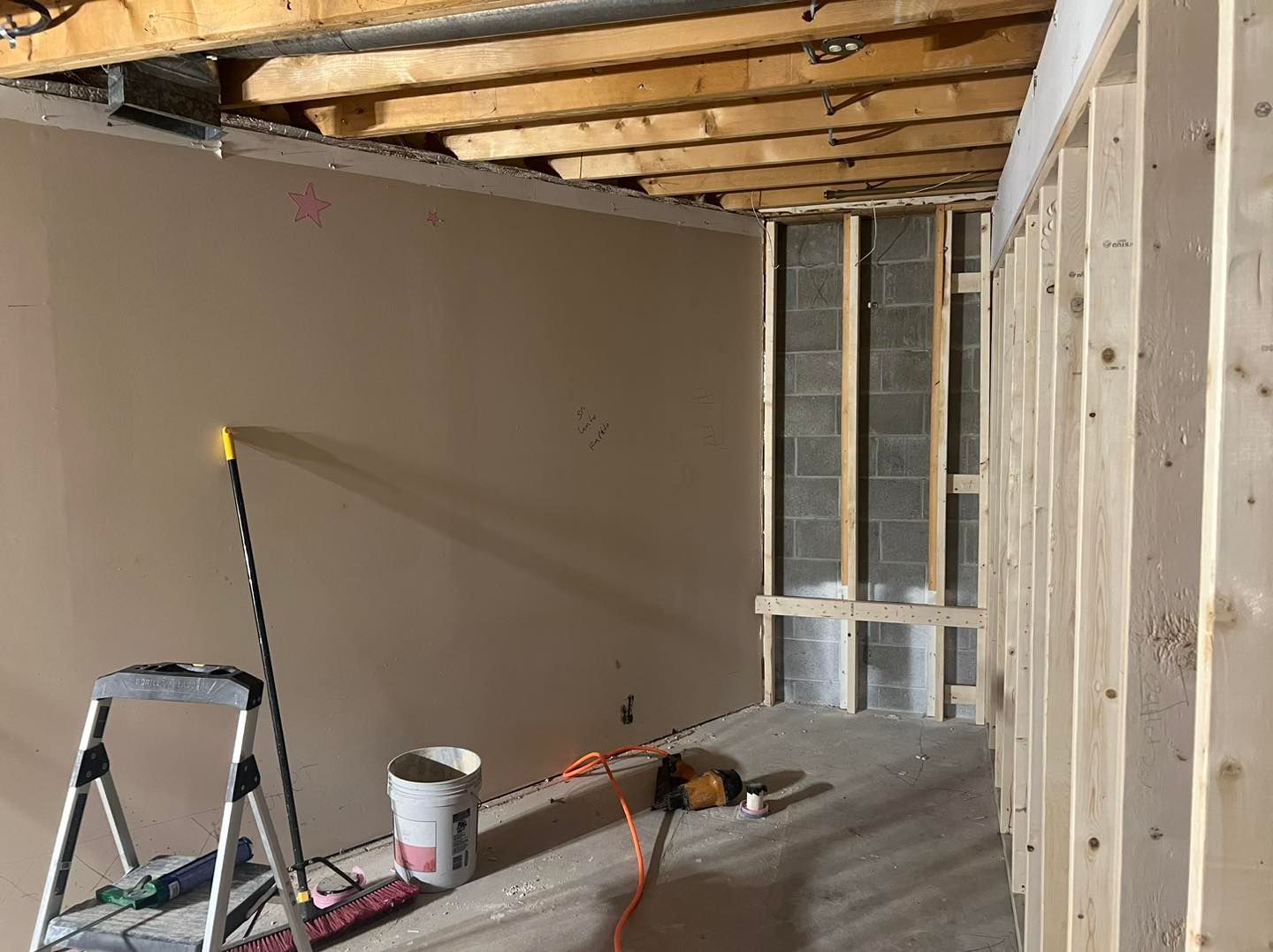 A room under construction with a ladder and a mop on the floor.
