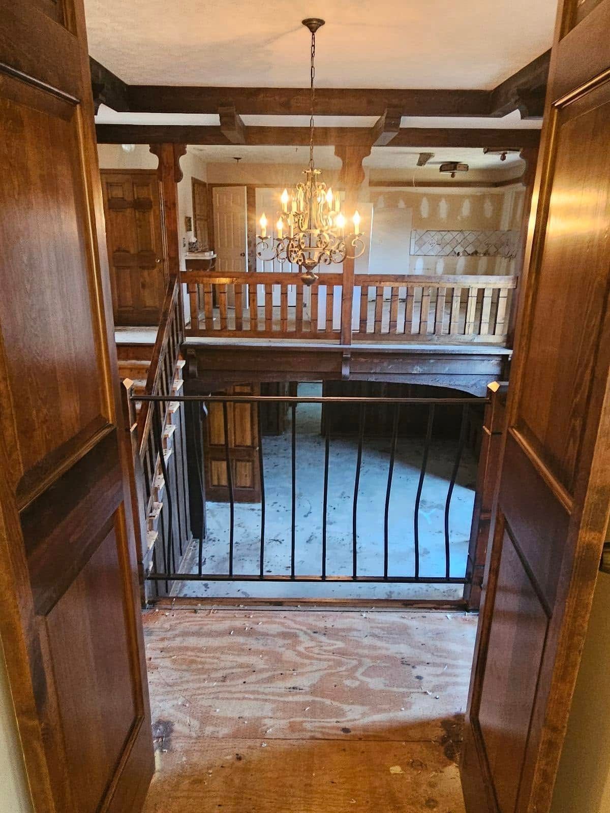 A wooden staircase with a wrought iron railing and a chandelier hanging from the ceiling.
