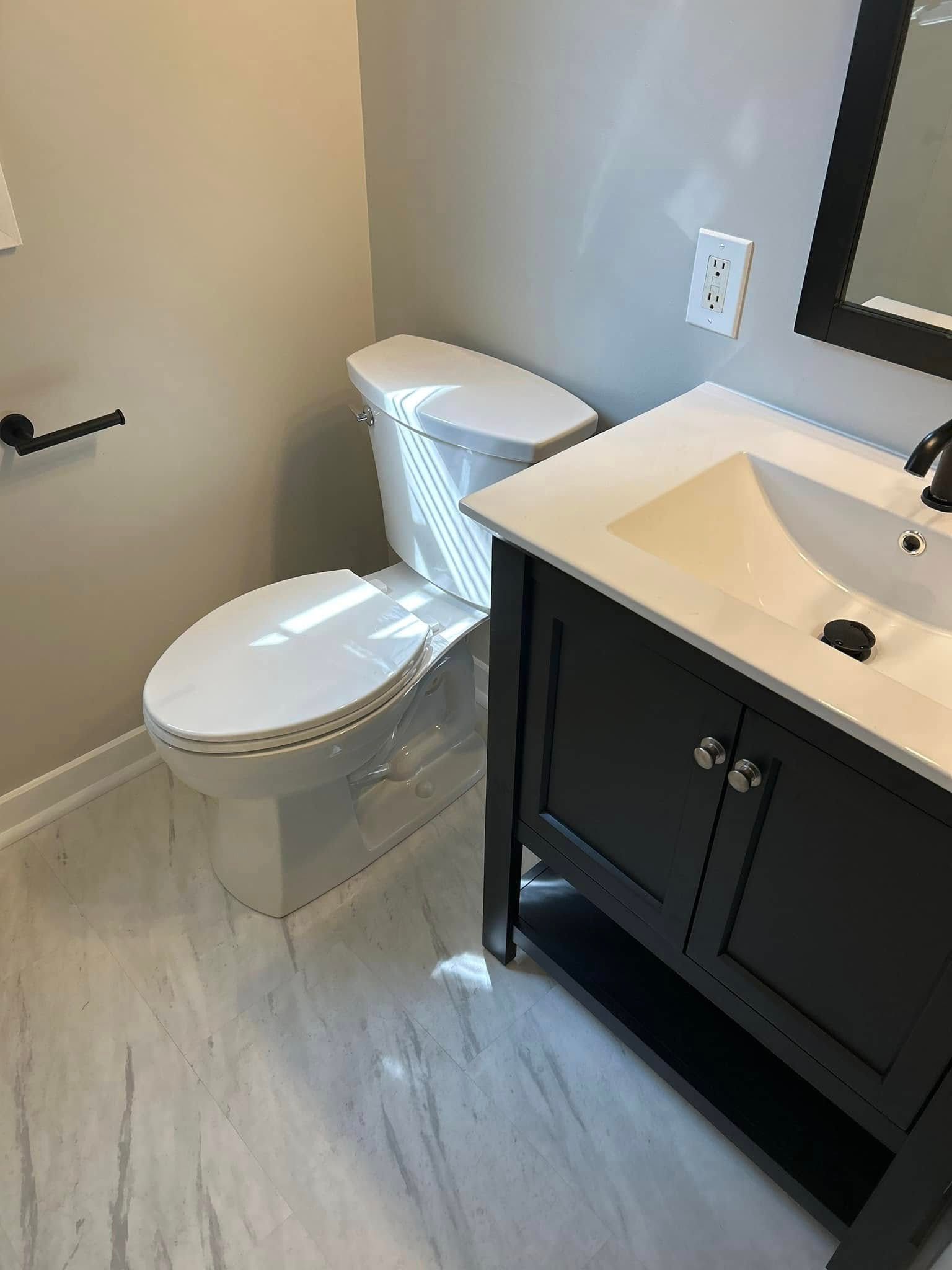 A bathroom with a toilet, sink, and mirror.