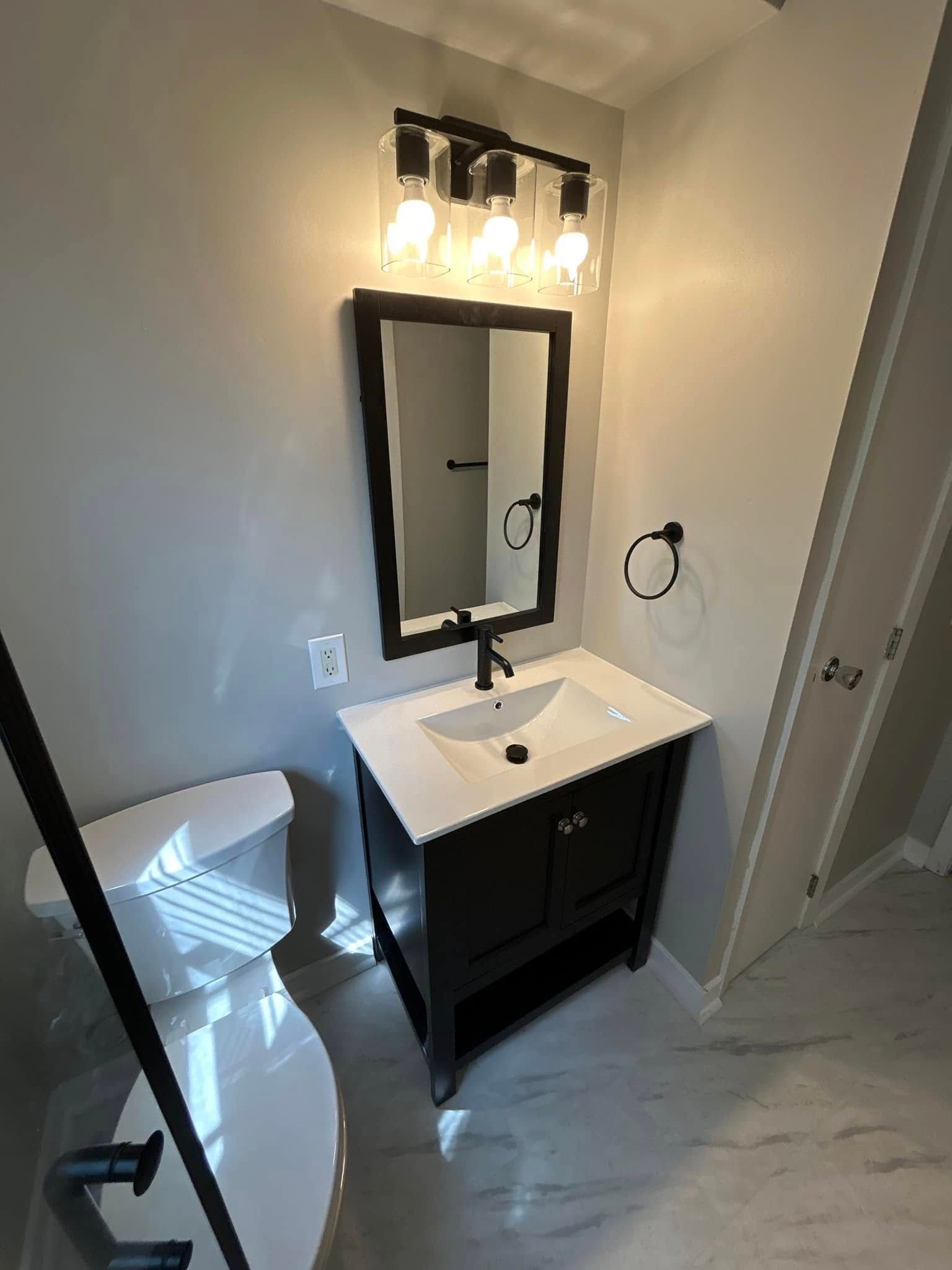 A bathroom with a sink, toilet and mirror.