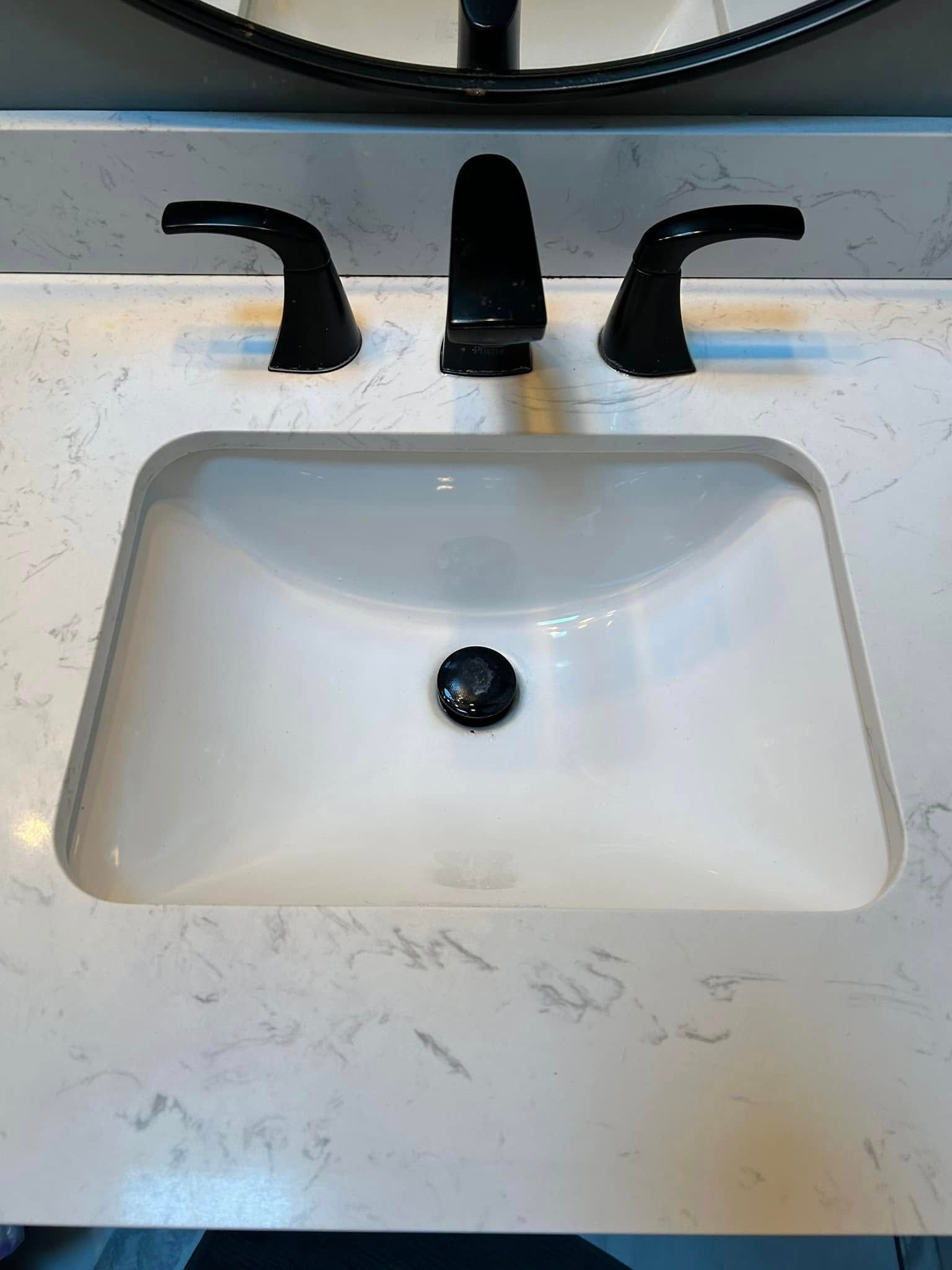 A bathroom sink with a black faucet and a mirror.