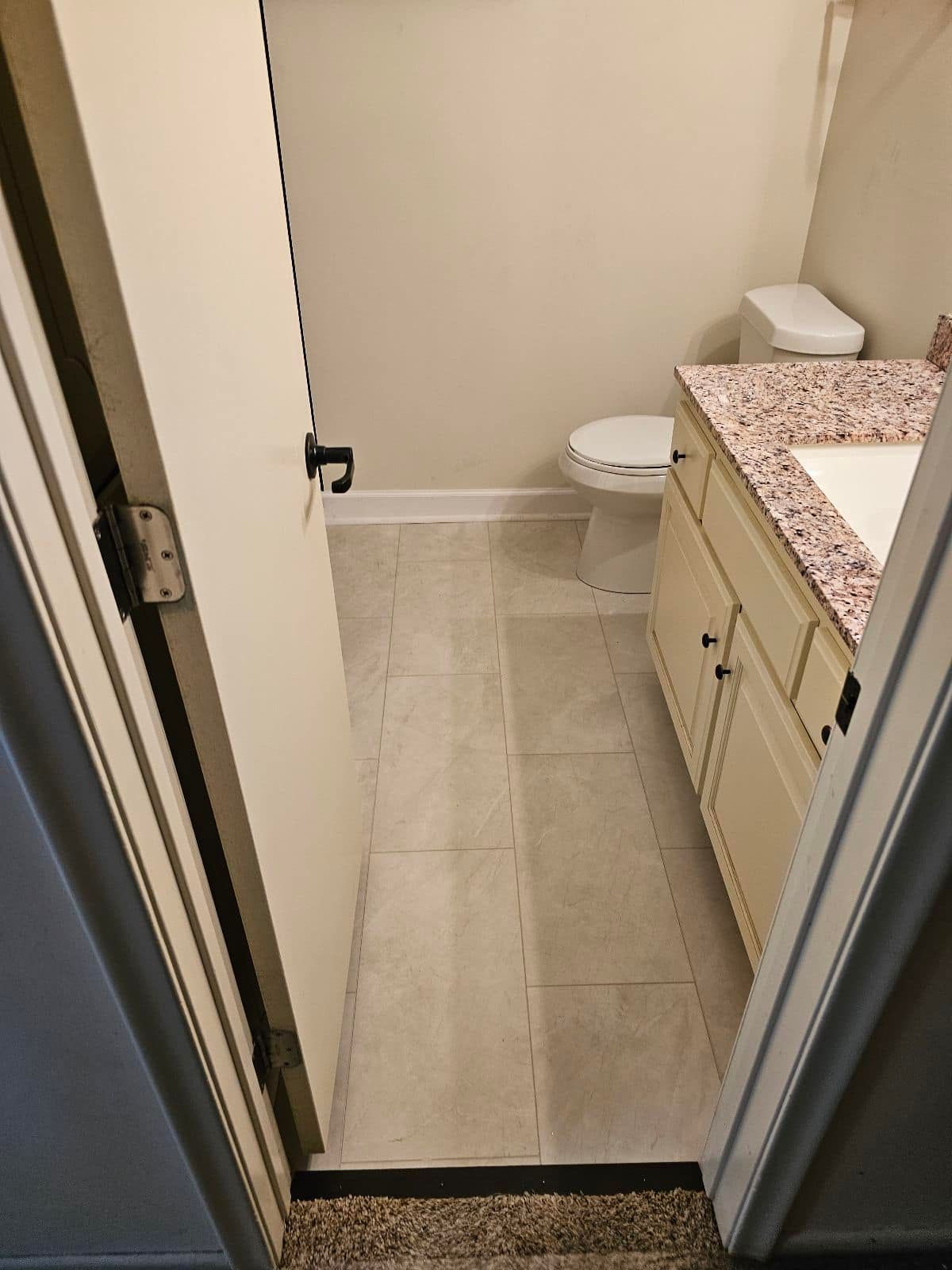 A bathroom with a toilet, sink, and cabinets.