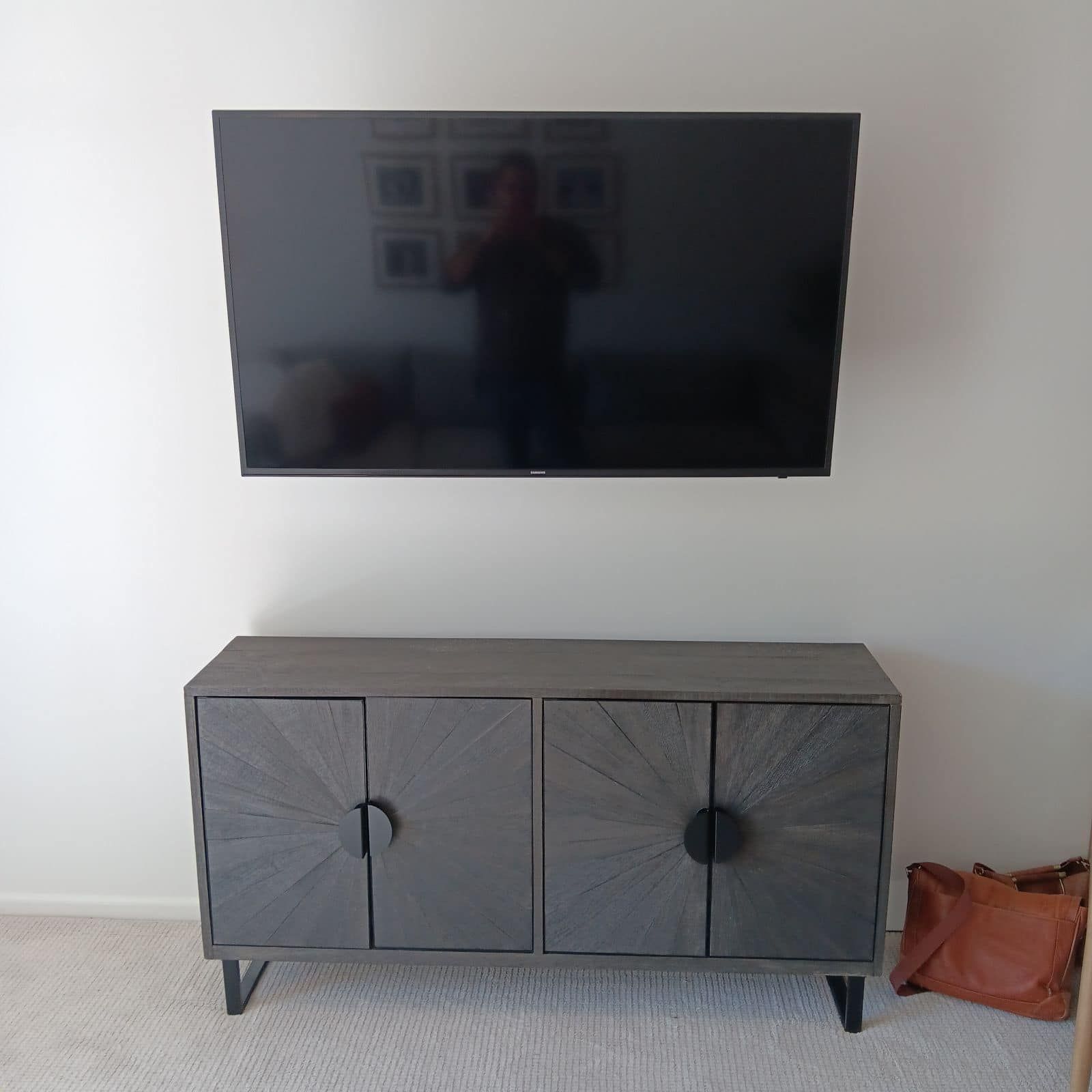 A flat screen TV is mounted to the wall above a gray cabinet.