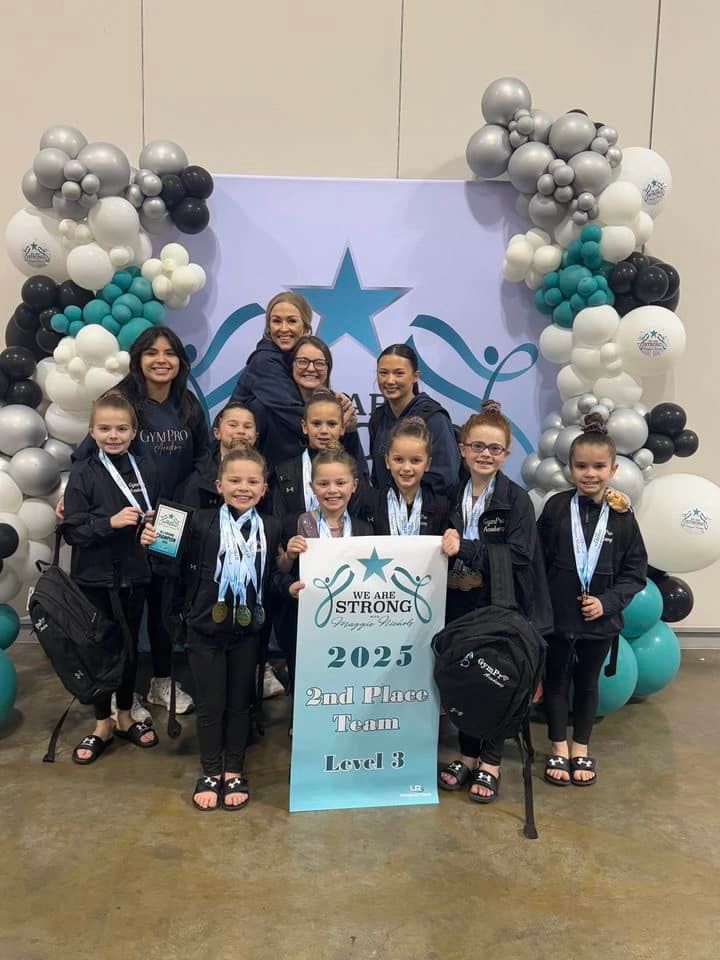 A group of young girls are posing for a picture in front of balloons.