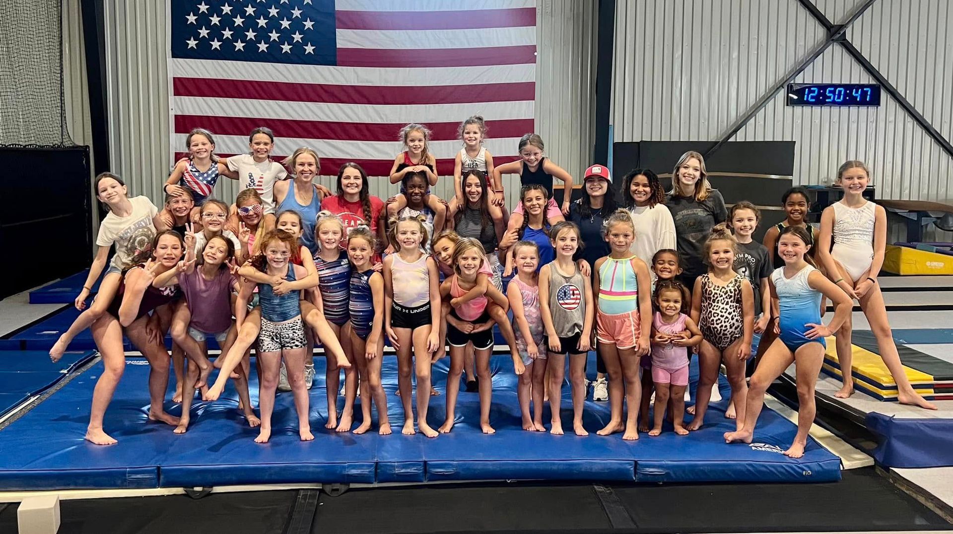A group of young girls are posing for a picture in front of an american flag.