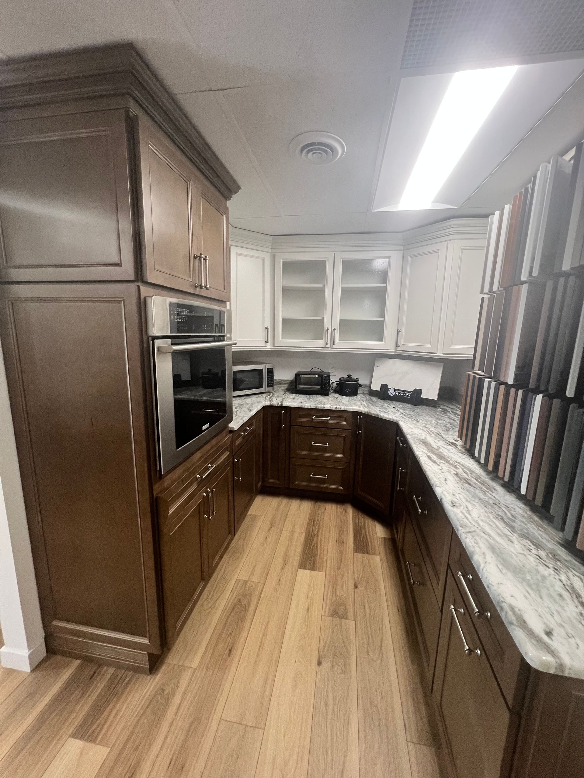 A kitchen with wooden cabinets and marble countertops in a showroom.