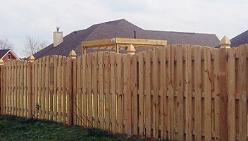 A wooden fence in front of a house with a gazebo in the background.