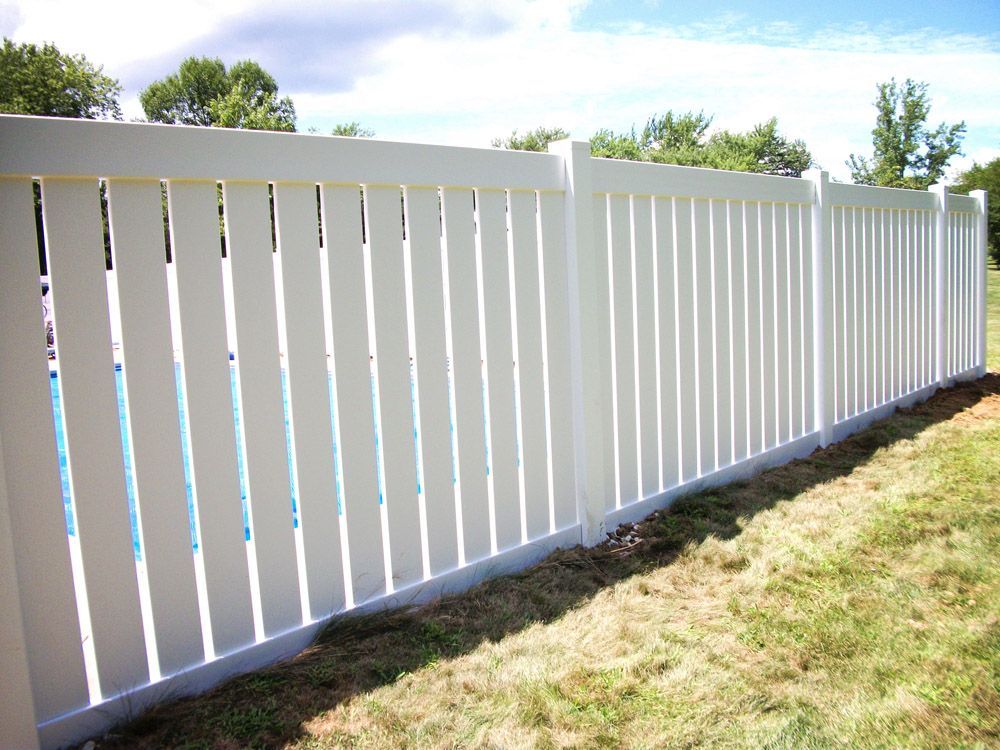 A white fence surrounds a swimming pool in a backyard.