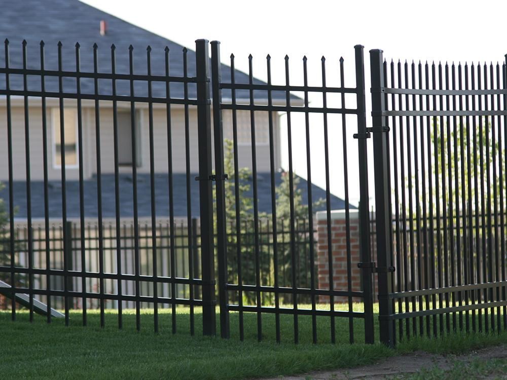 A black fence with a gate in front of a house