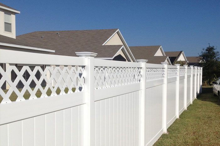 A white fence surrounds a row of houses in a residential area.