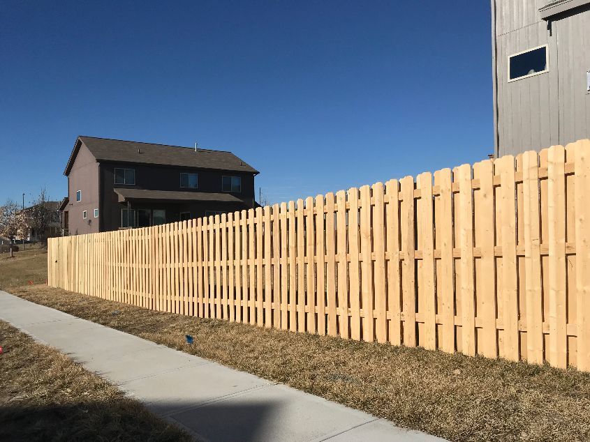 A wooden fence along a sidewalk next to a house.