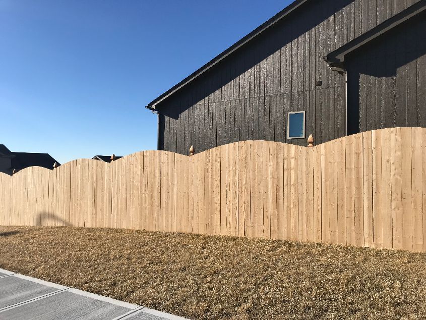 A wooden fence is in front of a black house.