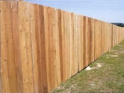 A long wooden fence is sitting in the middle of a grassy field.
