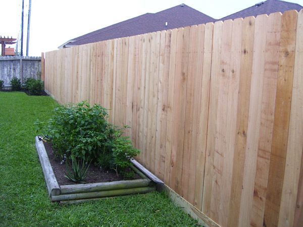 A wooden fence surrounds a garden in a backyard