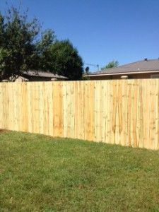 A wooden fence is in the middle of a lush green yard.
