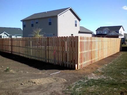 A wooden fence is in the backyard of a house.