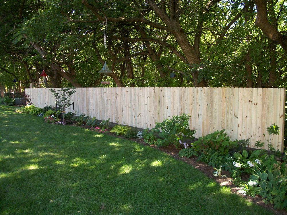 A wooden fence surrounds a lush green yard