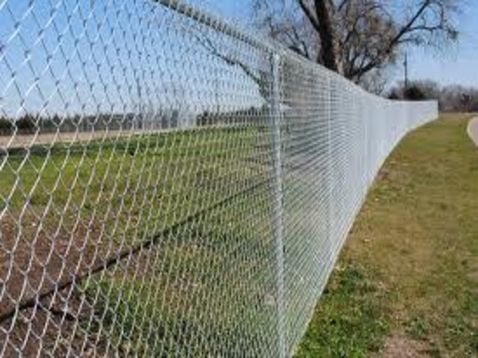A chain link fence is surrounding a grassy field.