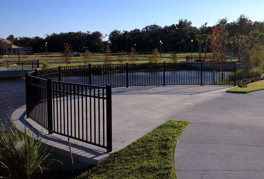 A black fence surrounds a pond in a park