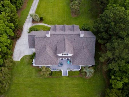 An aerial view of a large house surrounded by trees and grass.