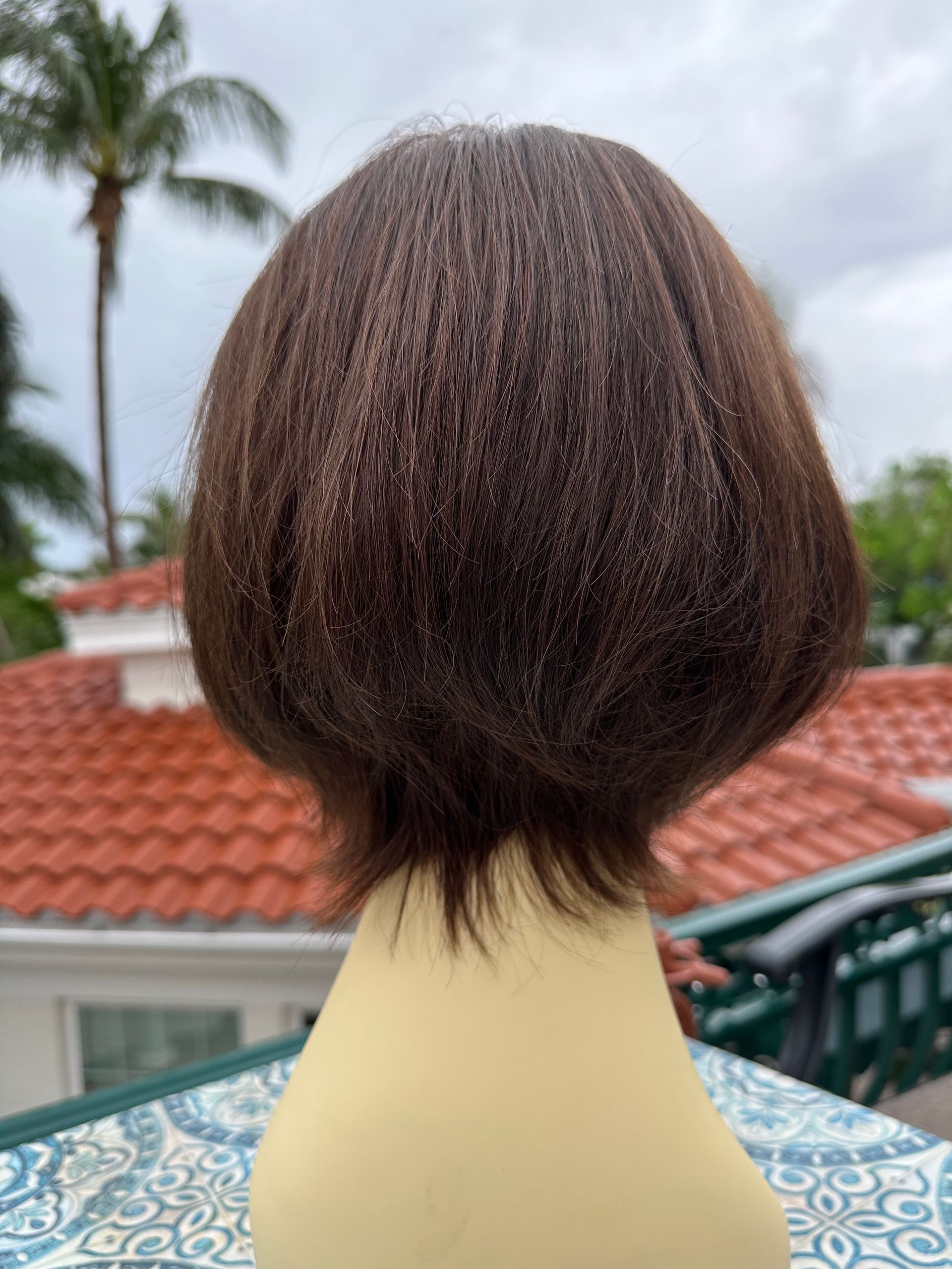 A wig is sitting on a table in front of a roof.