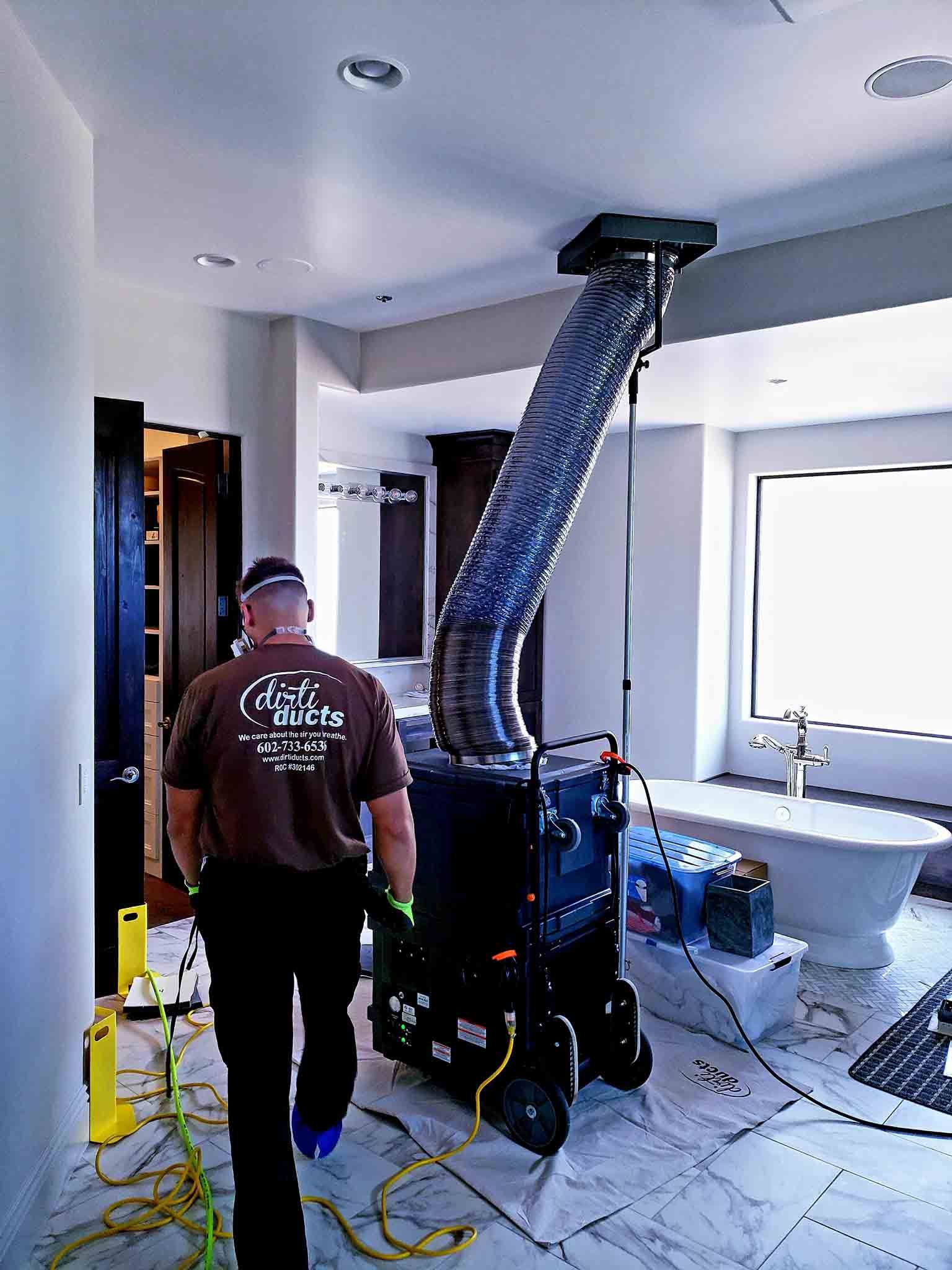 A man in a brown shirt is walking in a bathroom.