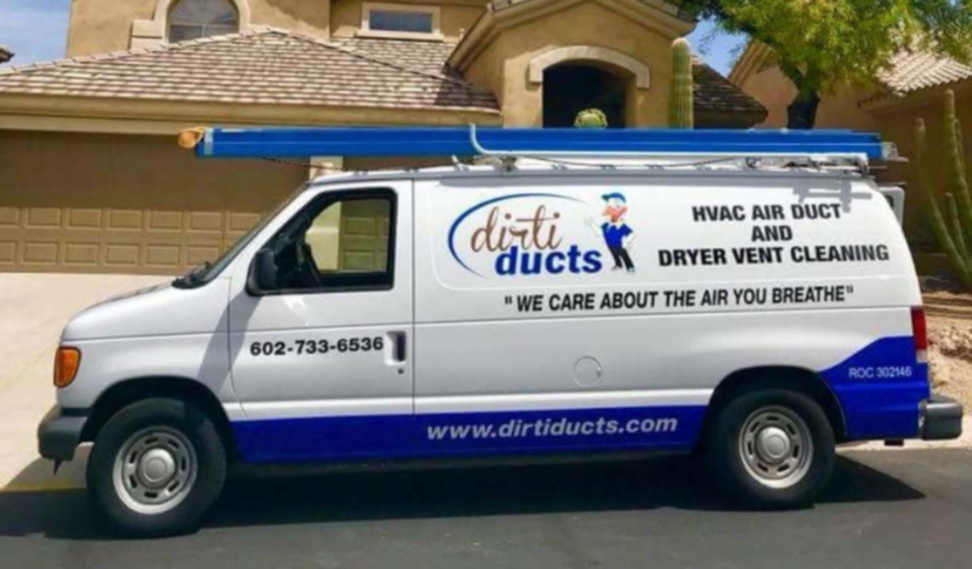 A white and blue van is parked in front of a house.