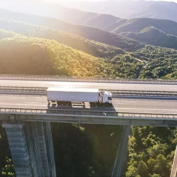 An aerial view of a truck driving over a bridge.