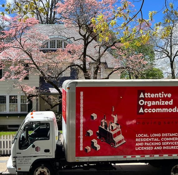 A truck that says attentive organized accommodations is parked in front of a house
