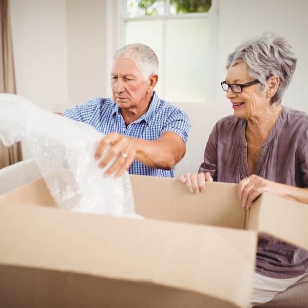 A man and a woman are opening a cardboard box.
