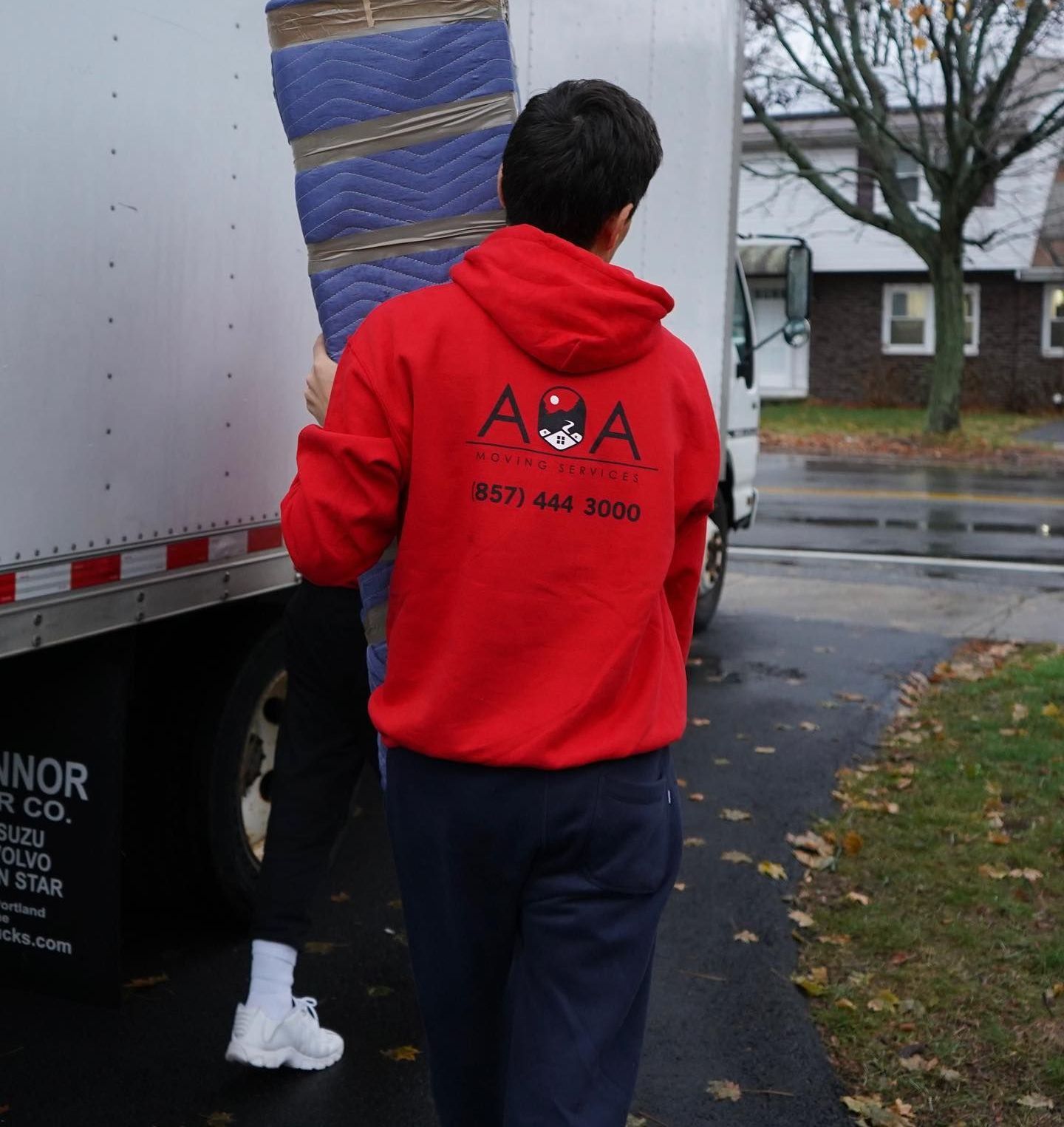 A man wearing a red aaa sweatshirt is carrying a blue blanket