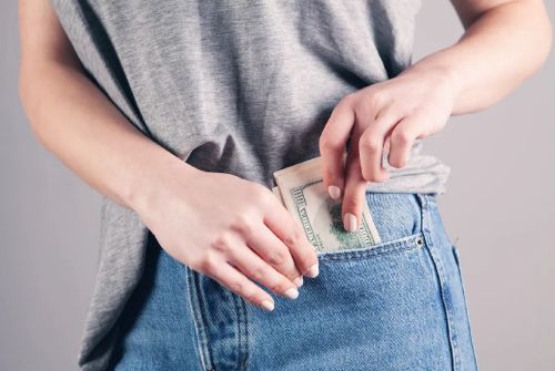 A woman is putting money in her jeans pocket