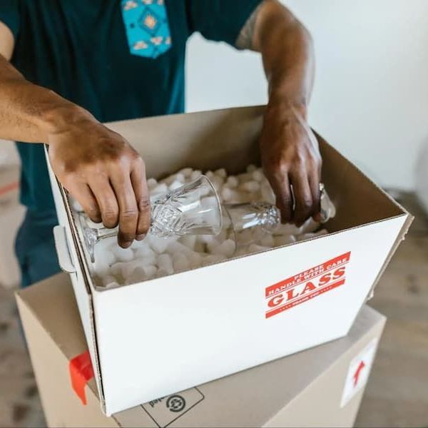A man is putting a glass in a box that says glass on it