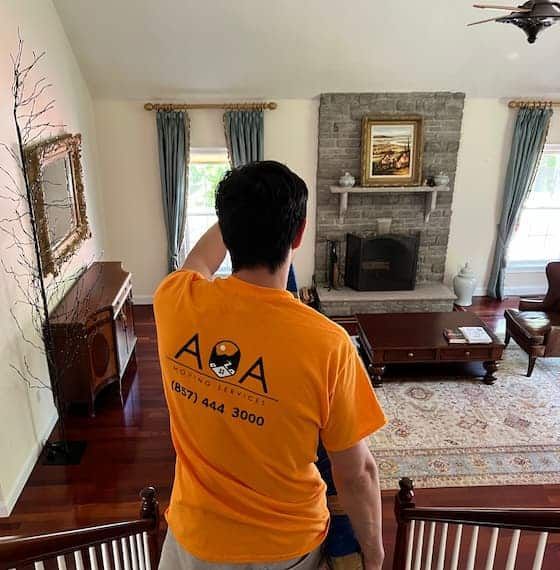 A man wearing an aoa shirt stands in a living room