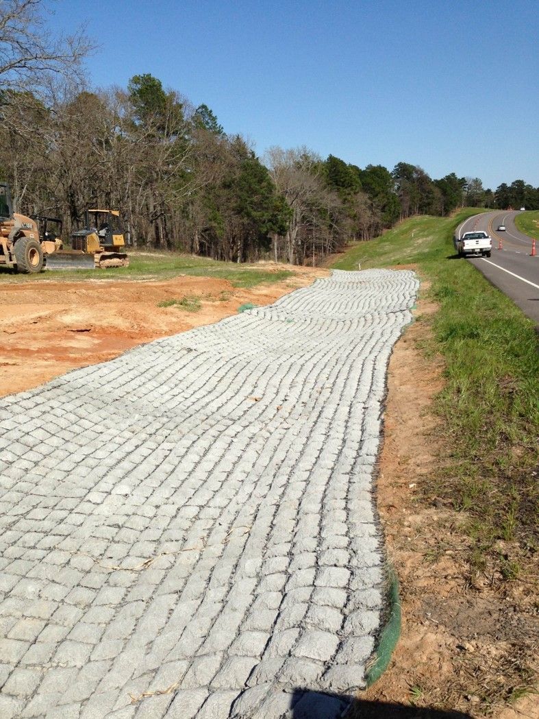A brick walkway is being built next to a highway.