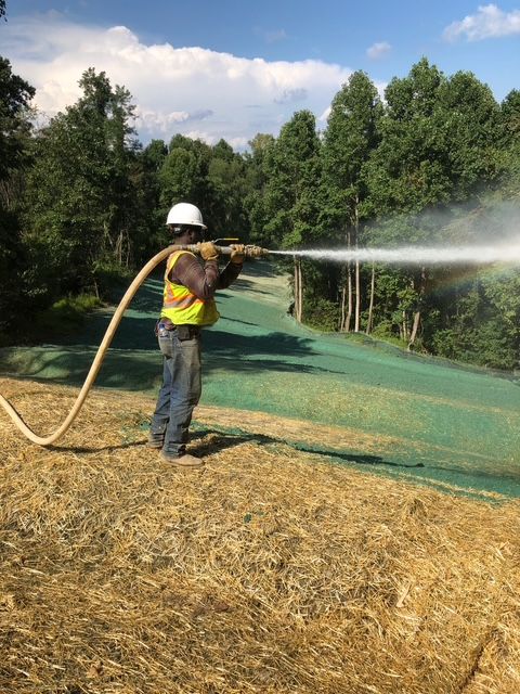 A man is spraying a field with a hose.