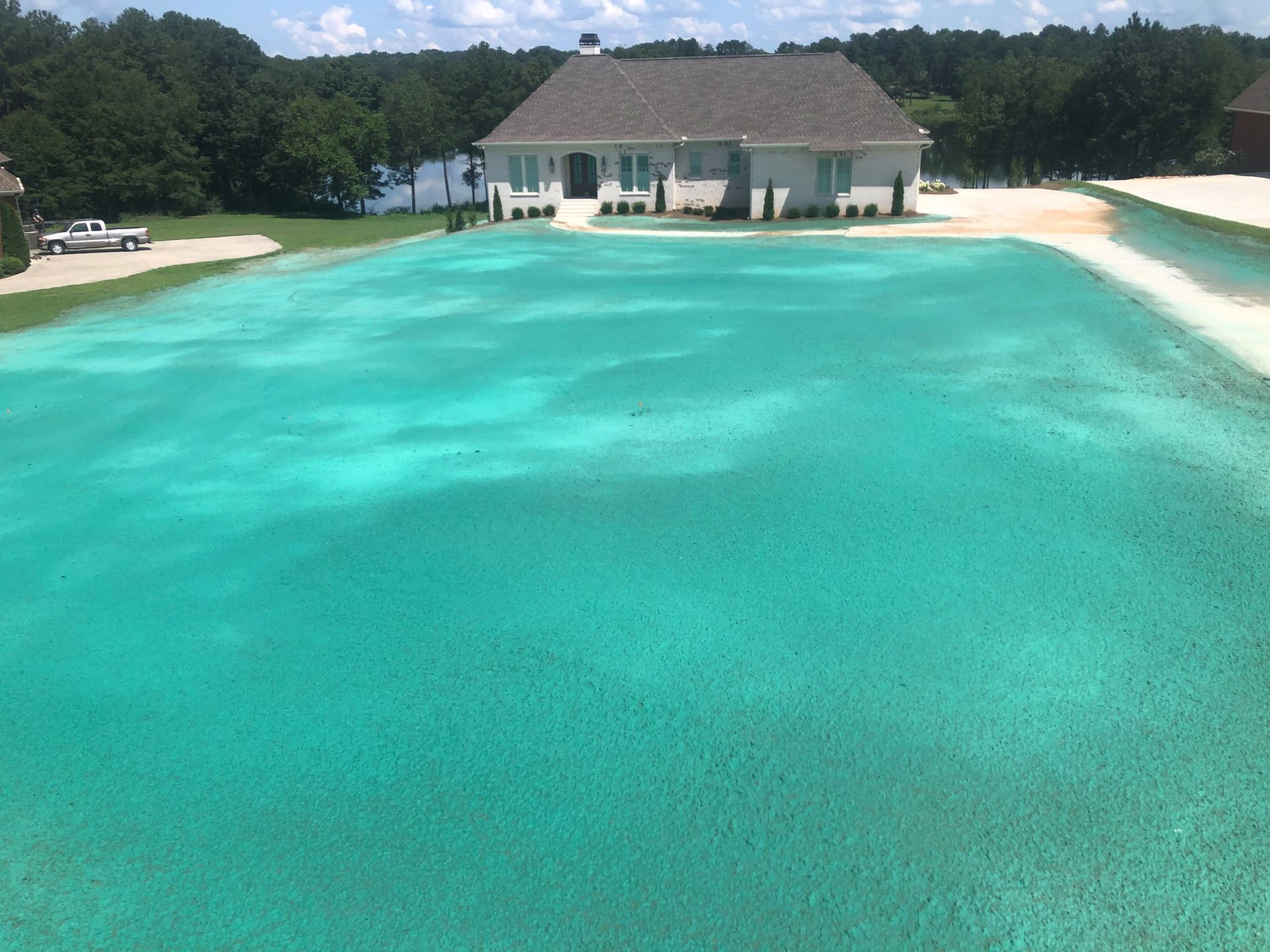 A large swimming pool with a house in the background.