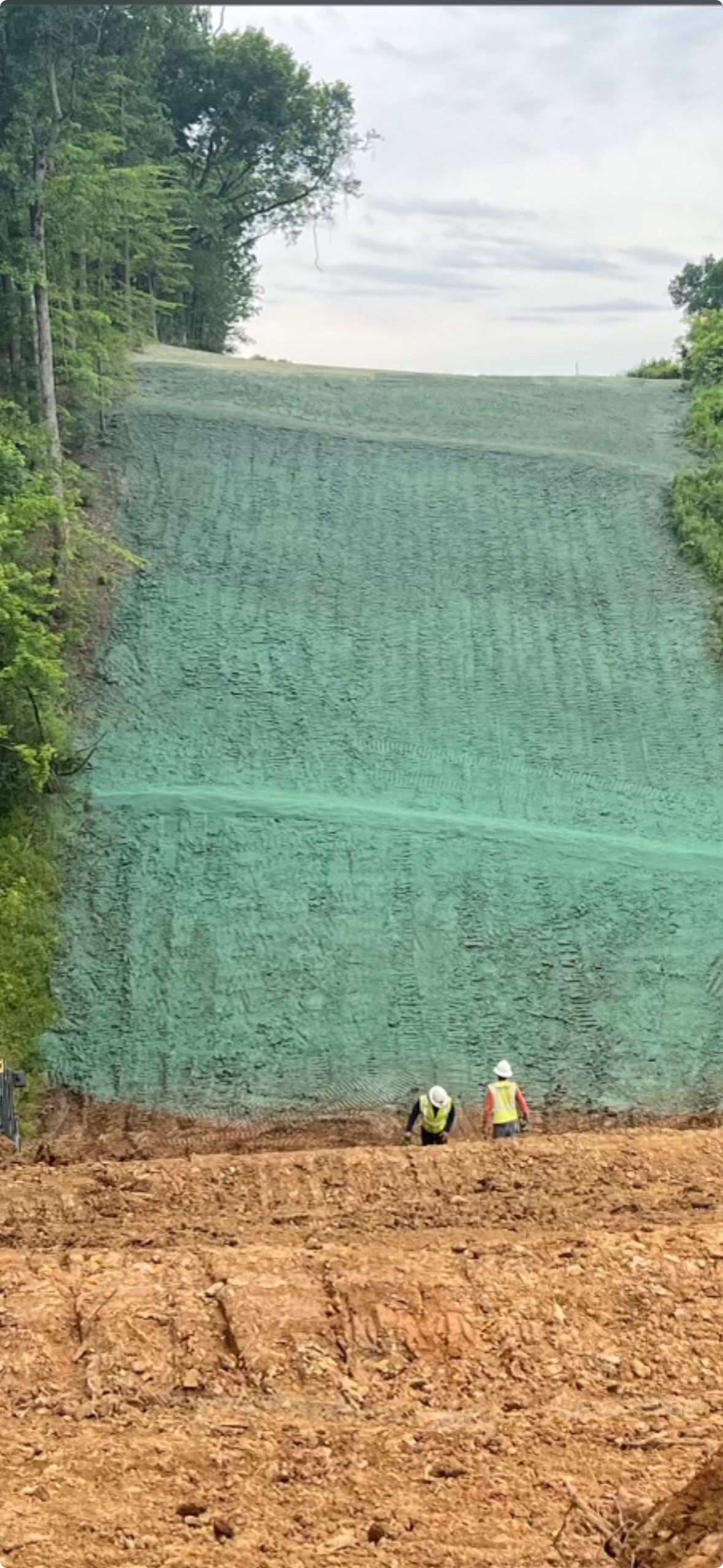 A group of people are standing on top of a dirt hill.