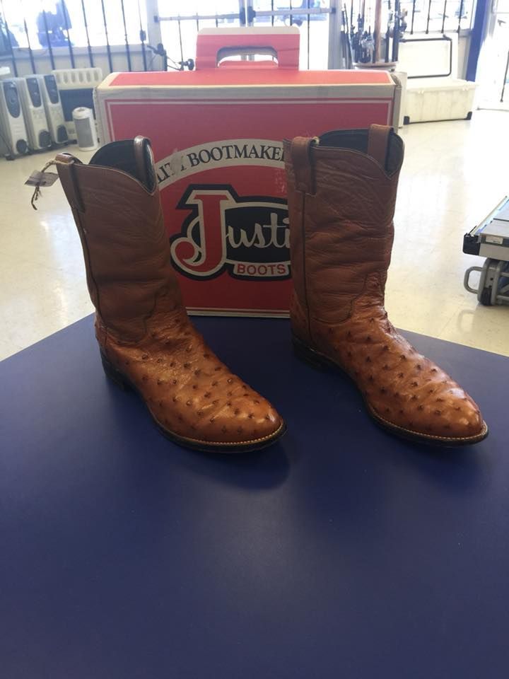Pair of brown Justin ostrich cowboy boots with a Justin Bootmaker cooler on a blue surface.