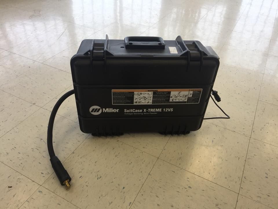 Black Miller welding machine on a light-colored floor with a long cable extending out.