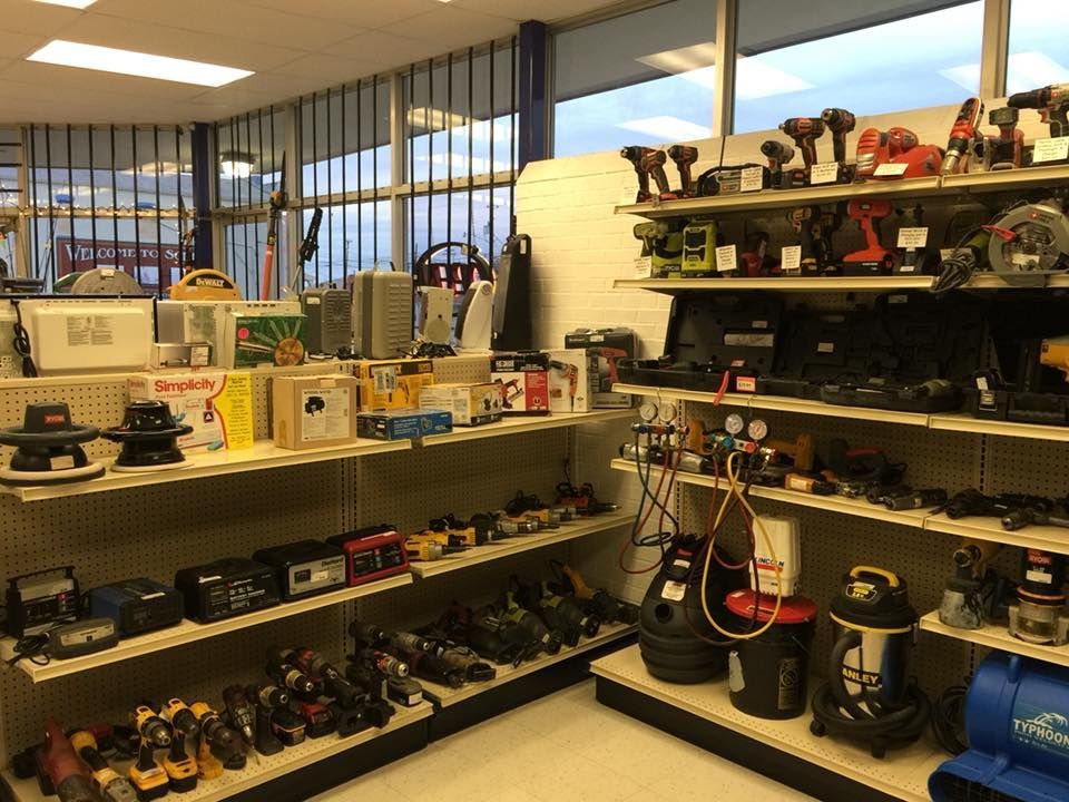 Shelves stocked with power tools and appliances in a store. Well-lit interior.